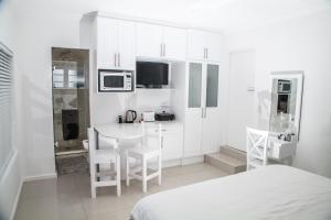 a white kitchen with a table and a microwave at Studio On Sea in Wilderness