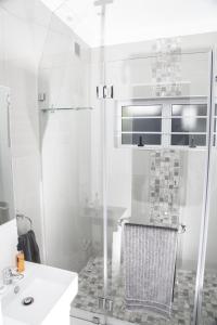 a white bathroom with a shower and a sink at Studio On Sea in Wilderness