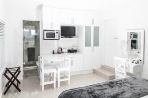 a white kitchen with a table and a microwave at Studio On Sea in Wilderness