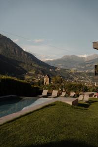 a pool with lounge chairs and a view of the mountains at Garni-Hotel Der Forsterhof in Lagundo