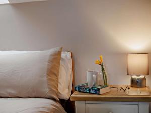 a bed with a table with a vase of flowers and a lamp at 2 Bed in Beaworthy oc-87085 in Highampton +10 photos