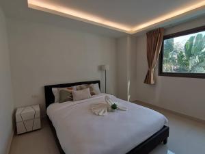 a bedroom with a large white bed with a window at คลับรอยัล2bed in North Pattaya +86 photos