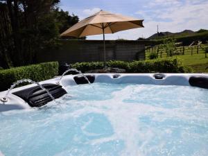 a hot tub with an umbrella in a yard at 4 Bed in Bideford oc-owlbr in Clovelly