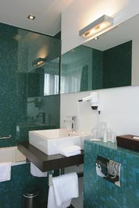 een badkamer met een wastafel en een spiegel bij Hotel Erzgiesserei Europe in München