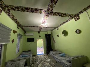 a room with green walls and a ceiling with a room with beds at Guest house Lovely Guest in Bukhara