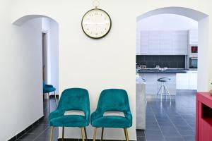 a kitchen with two green chairs and a clock on the wall at GIKLA MAISON in Catania