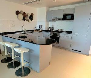 a kitchen with a counter and some stools in it at Family Floatie Flat with Pool & Workspace in As Sīfah