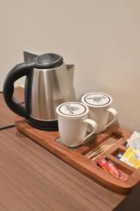 a tea kettle and two cups on a wooden tray at Hotel Phantom in Gangānagar