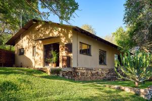 a small house with a stone facade and a yard at Parsons River Camp in Balule Game Reserve