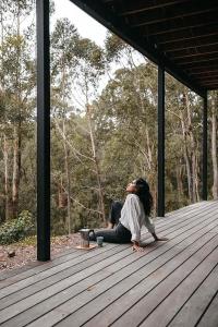 a woman sitting on a wooden deck at Stunning Bush Beach House! NEW! in Elizabeth Beach