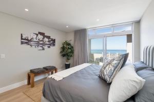 a bedroom with a bed and a large window at Elegant Beach front Villa in Bloubergstrand +77 photos
