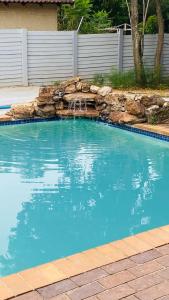 a swimming pool with a waterfall in a yard at Fourways Luxury Residence in Four Ways
