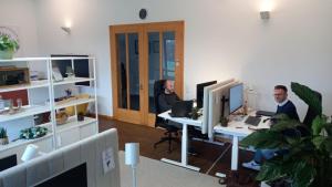 two people sitting at desks in an office at Apartment An der Weinstraße in Oberotterbach