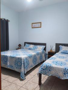 a bedroom with two beds with blue and white sheets at Casa de praia in Peruíbe +11 photos