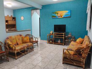 a living room with chairs and a flat screen tv at Casa de praia in Peruíbe