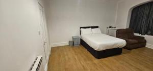 a bedroom with a bed and a couch and a chair at Spacious Two Bedroom Flat with Dedicated Workspace in Worsley in Worsley