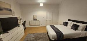 a bedroom with a bed and a flat screen tv at Spacious Two Bedroom Flat with Dedicated Workspace in Worsley in Worsley