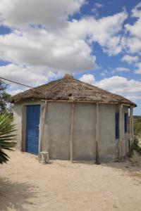 a small building with a blue door and a grass roof at Espace baleine Anakao in Anakao