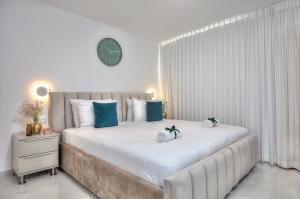a white bedroom with a large bed with blue pillows at Mountain Top Views -205- נופי פסגות in Safed