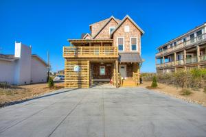 a house with a wrap around porch on a driveway at 4115 - Coastal Cottage in Kitty Hawk