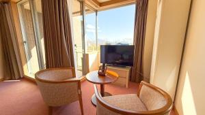 a hotel room with a television and a table and chairs at Livemax Resort Yatsugatake Kogen in Hokuto