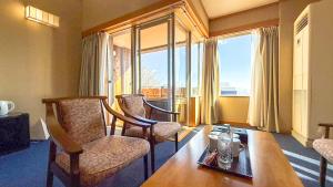 a living room with a table and chairs and a large window at Livemax Resort Yatsugatake Kogen in Hokuto
