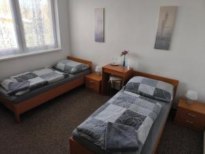 two beds in a room with a desk and a bed sidx sidx sidx at Penzion Jarka in Bratislava
