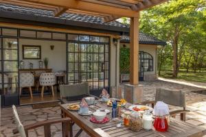 a patio with a wooden table with food on it at The Maa Guest House in Talek +24 photos