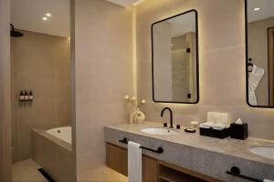 a bathroom with two sinks and a tub and a mirror at The H Dubai in Dubai
