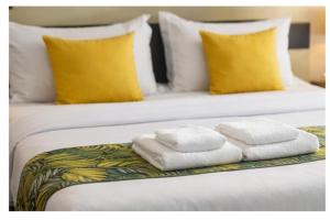 two white towels on a bed with yellow pillows at Covenant Crest Hotel in Accra