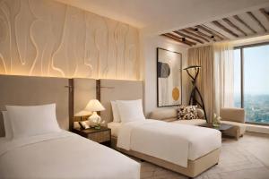 a hotel room with two beds and a couch at The H Dubai in Dubai