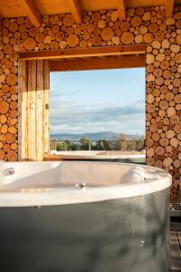 a bath tub in a room with a large window at Cocooon Wood, hébergement insolite Savoie in Saint-Paul-sur-Yenne