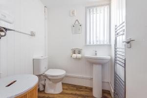 a white bathroom with a toilet and a sink at Violet in Heacham +18 photos
