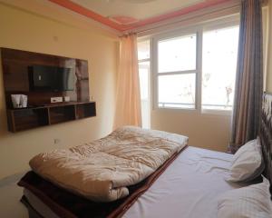 a bedroom with a bed and a tv and a window at Corn Village Retreat in Mussoorie