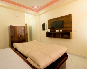 a bedroom with a bed and a flat screen tv at Corn Village Retreat in Mussoorie