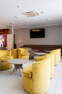 a restaurant with yellow chairs and a table and a tv at Hotel Aurora in Mamaia
