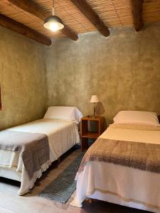 a bedroom with two beds and a table with a lamp at Cabana Mirador Sumajpacha in Tilcara