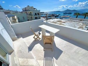 a table and chair on a balcony with a view of the water at Castellino Naxos in Naxos Chora
