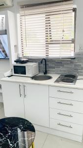 a white kitchen with a sink and a microwave at Fourways Luxury Residence in Four Ways
