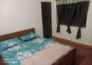 a bedroom with a bed with blue comforter and pillows at Nalukettu Veedu in Thottada