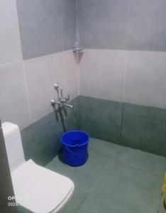 a bathroom with a toilet and a blue bucket at Nalukettu Veedu in Thottada