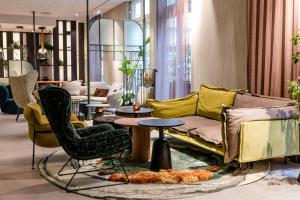 a living room with a couch and chairs and tables at Motel One Frankfurt-Hauptbahnhof in Frankfurt