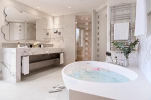 ein weißes Badezimmer mit Badewanne und Waschbecken in der Unterkunft Hotel Eden Roc - The Leading Hotels of the World in Ascona + 52 Fotos