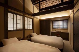 a bedroom with two beds and a desk and windows at Choya Goshominami Machiya House in Kyoto