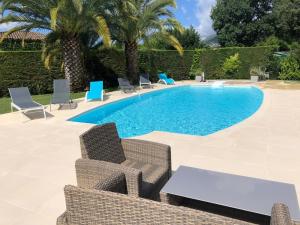 a swimming pool with chairs and a table next to it at Charmante villa familiale in Vence