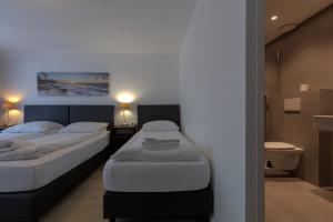 two twin beds in a room with a bathroom at Hotel Randenbroek in Amersfoort