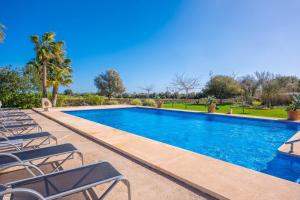 a swimming pool with lounge chairs and trees at Agroturismo Mondrago -Antic Na Martina- in Portopetro