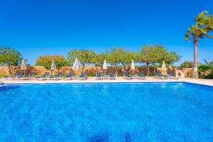 a large swimming pool with chairs and umbrellas at Agroturismo Mondrago -Antic Na Martina- in Portopetro