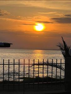 a sunset over the ocean with a fence at Sun N Sand in Ligia