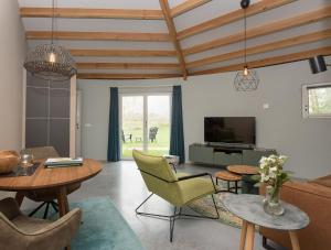 a living room with tables and chairs and a tv at Hoeve H-art, Silo 161, Uniek Drents silo-appartement met privé terras en rust in Ruinerwold